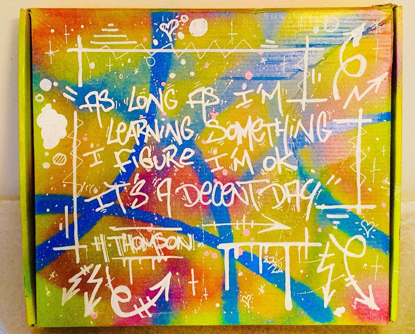 Dessus coffret — texte manuscrit sur fond multicolore